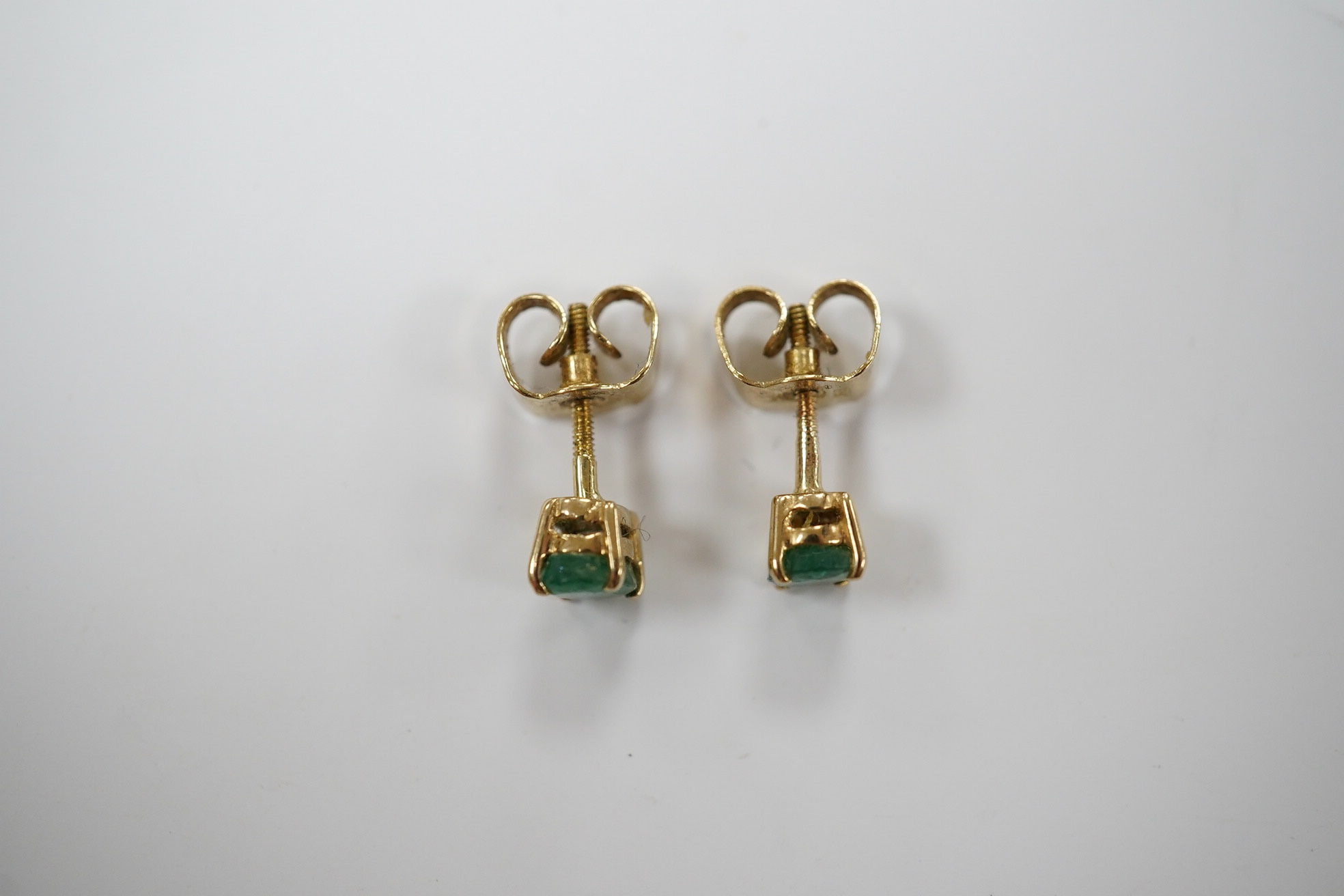 A pair of 9ct and solitaire oval cut emerald set ear studs, gross weight 1.2 grams. Condition - poor to fair